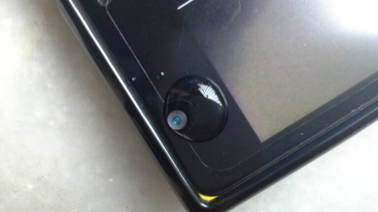 Close-up of a smartphone camera lens with a drop of water — a creative macro photography hack demonstrated by Humayunn Peerzaada.