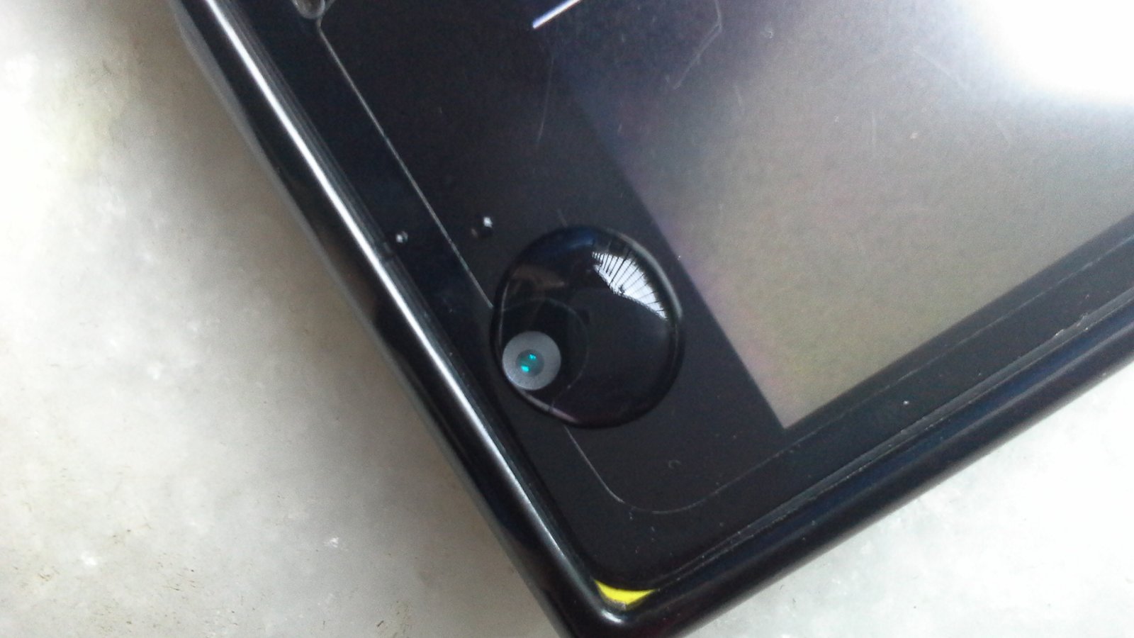 Close-up of a smartphone camera lens with a drop of water — a creative macro photography hack demonstrated by Humayunn Peerzaada.