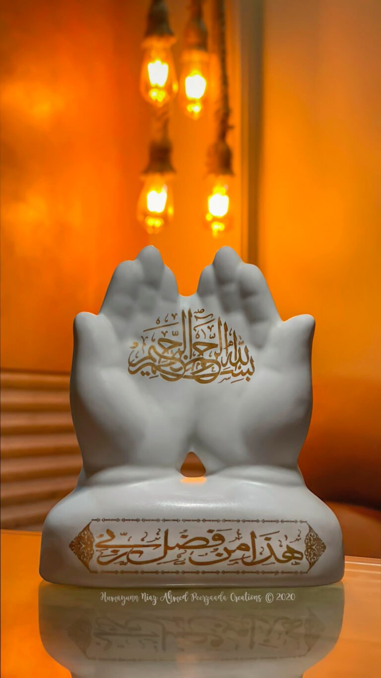 Hands sculpture with Arabic calligraphy “Bismillah ir-Rahman ir-Rahim” placed before glowing warm hanging lights — symbolizing prayer, gratitude, and divine blessings.