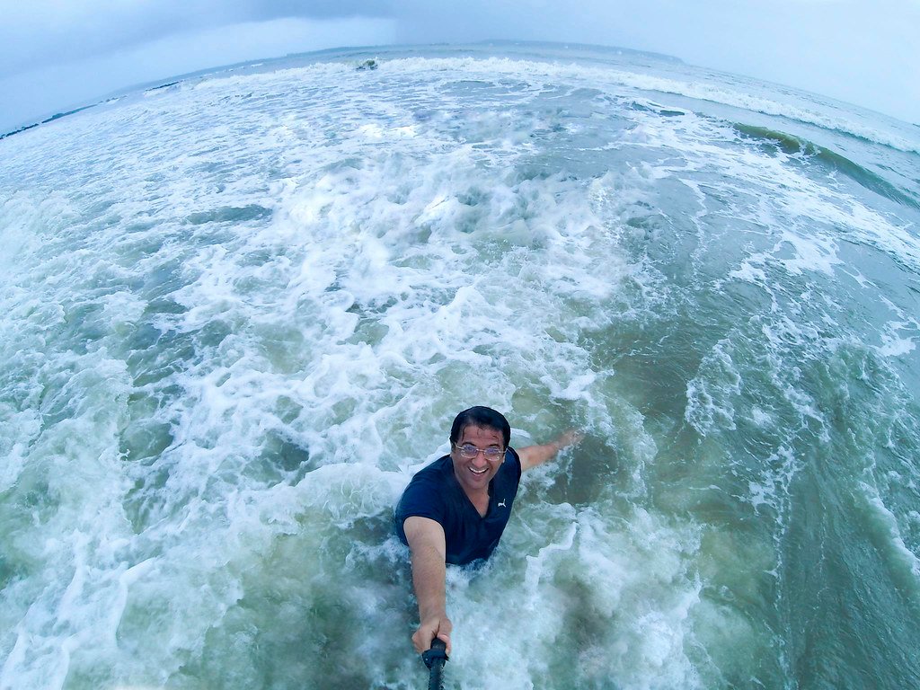 Humayunn Peerzaada standing fearlessly in the ocean waves — symbolizing courage, resilience, and the spirit of moving forward with the thought, “Lahron se ḍarkar nauka paar nahi hoti.