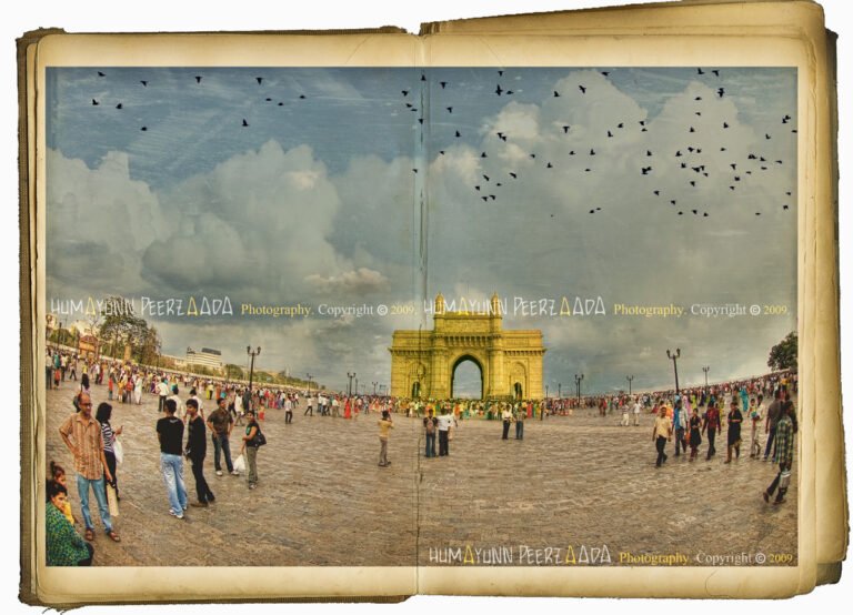 Gateway of India, Mumbai — a vintage-style photograph by Humayunn Peerzaada, depicting the iconic monument with a bustling crowd beneath a cloudy sky and birds soaring above.
