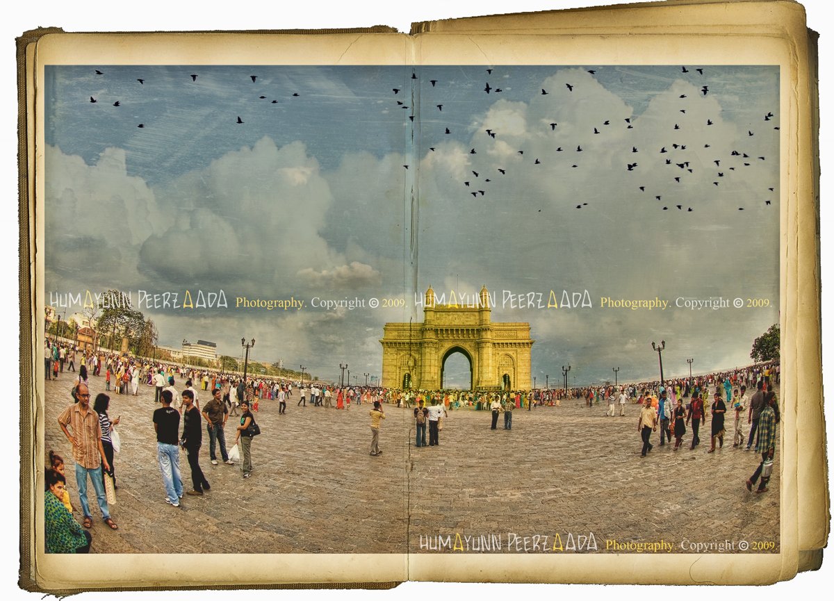 Gateway of India, Mumbai — a vintage-style photograph by Humayunn Peerzaada, depicting the iconic monument with a bustling crowd beneath a cloudy sky and birds soaring above.