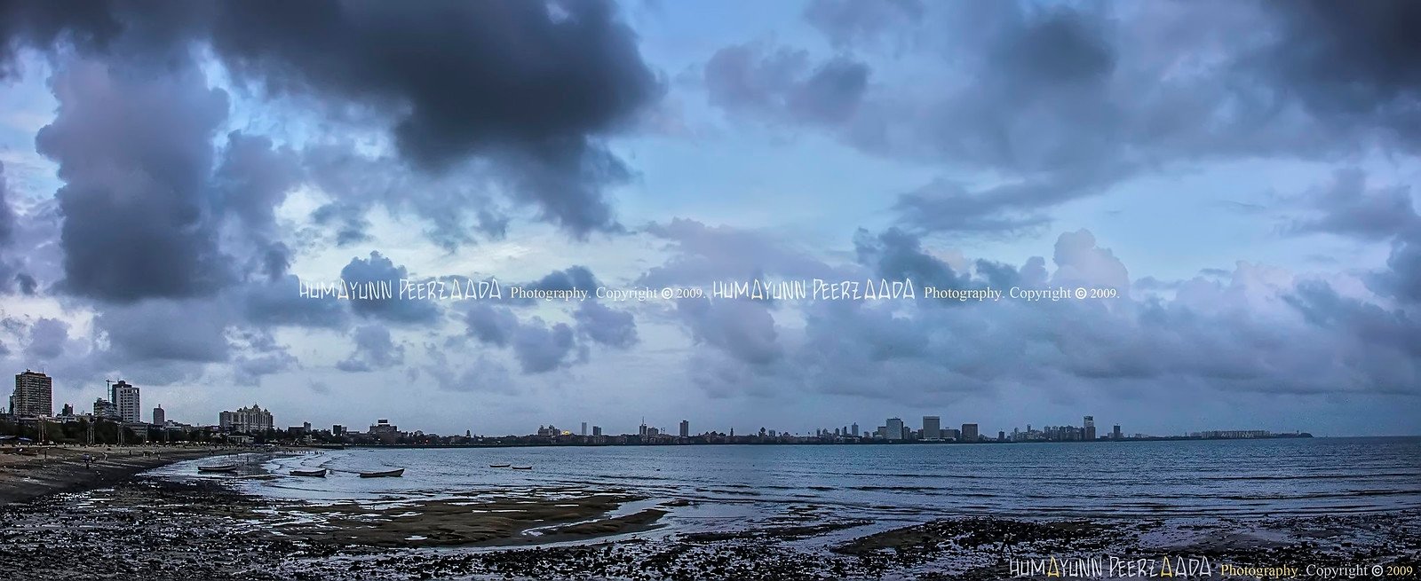 Panoramic view of Marine Drive, Mumbai — captured by Humayunn Peerzaada, showing the Arabian Sea, city skyline, and dramatic monsoon clouds.