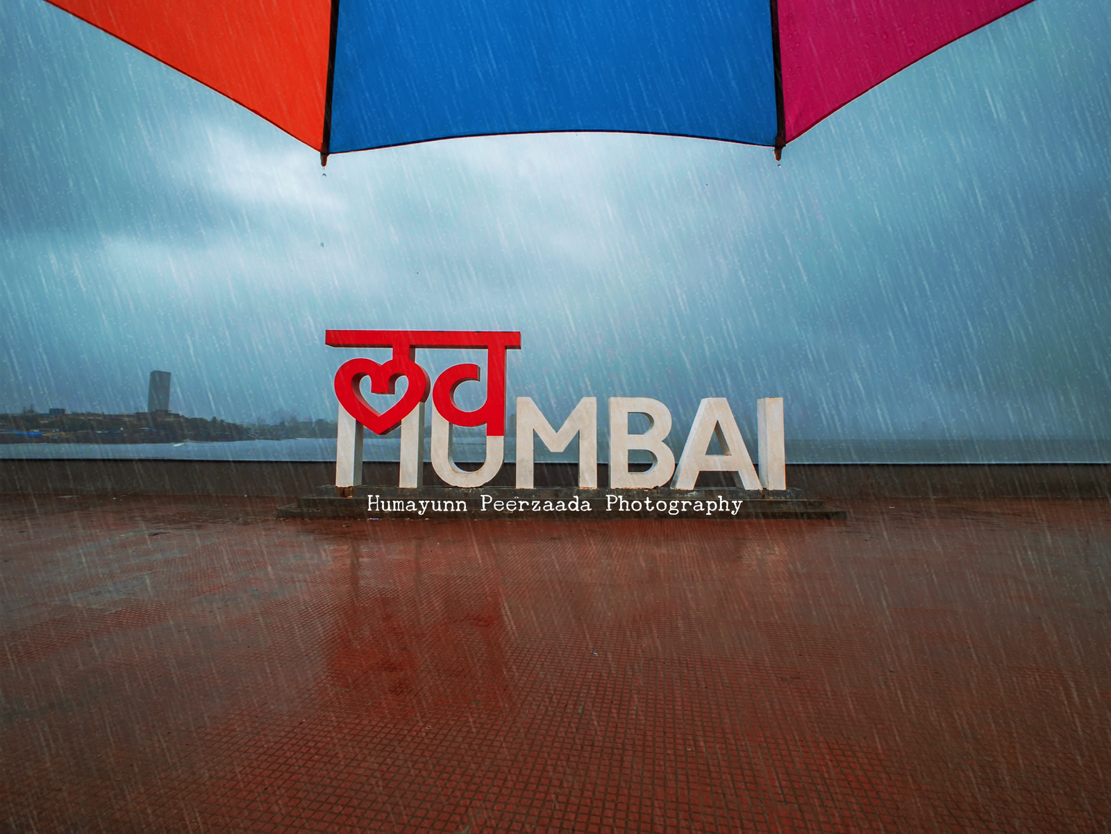 Rain-soaked streets of Mumbai with reflections of South Mumbai landmarks, captured during the monsoon season by Humayunn Peerzaada.