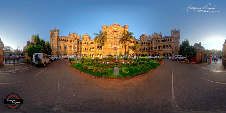 360° panoramic photograph of Chhatrapati Shivaji Maharaj Terminus (CSMT) in Mumbai, India — highlighting its majestic Gothic architecture, landscaped gardens, and vibrant cityscape under a clear blue sky.