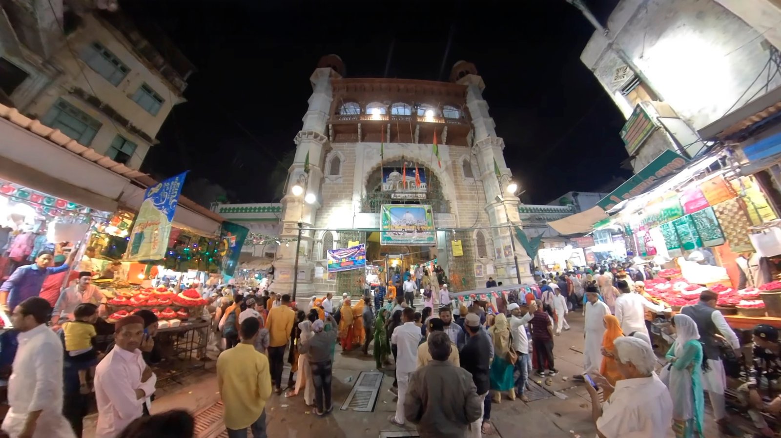 Buland Darwaza at Sarwar Sharif Dargah, Ajmer — exterior night view with devotees and city lights.
