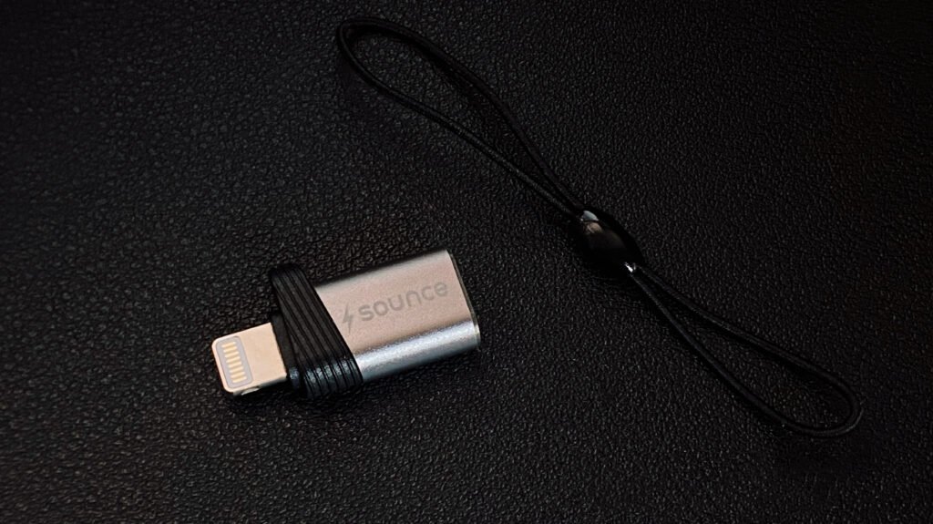 Compact premium Type-C to Lightning adapter for iPhone photographed on a black textured background.