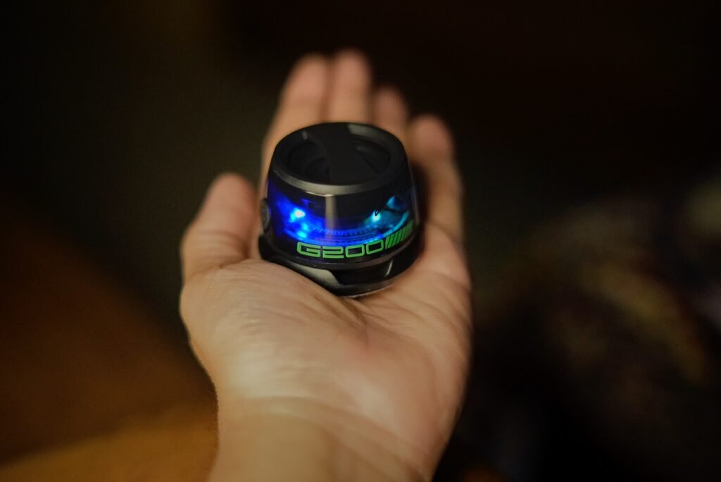 A compact magnetic Bluetooth speaker with blue LED lights resting in a person’s open palm, showing its small size and portable design.