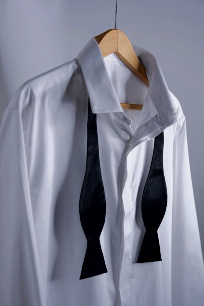 White shirt with black bow styling on hanger – minimal clean men’s fashion look
